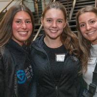 Three event attendees standing close together and smiling for camera